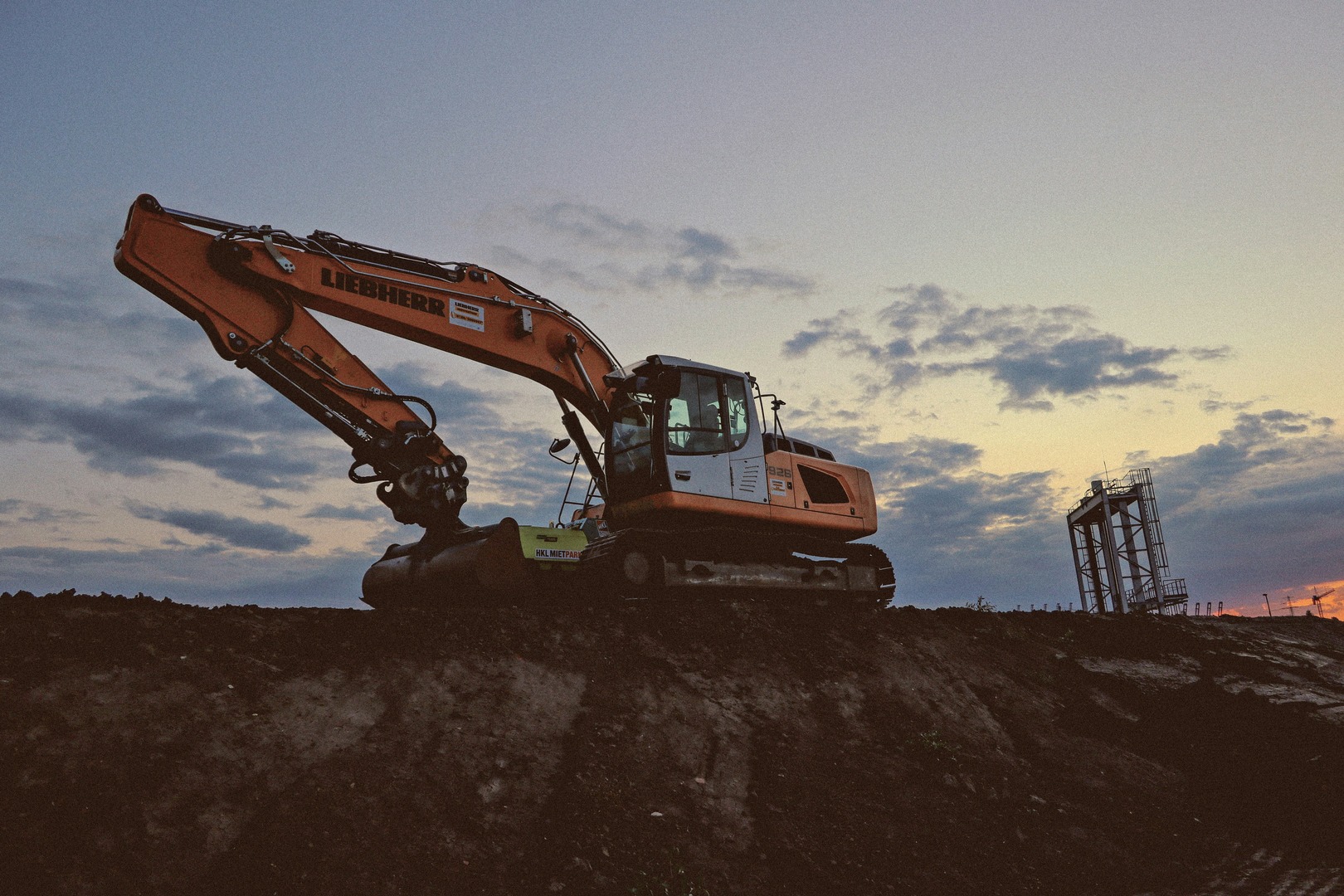 Digger on a hill during dusk with sky in the background