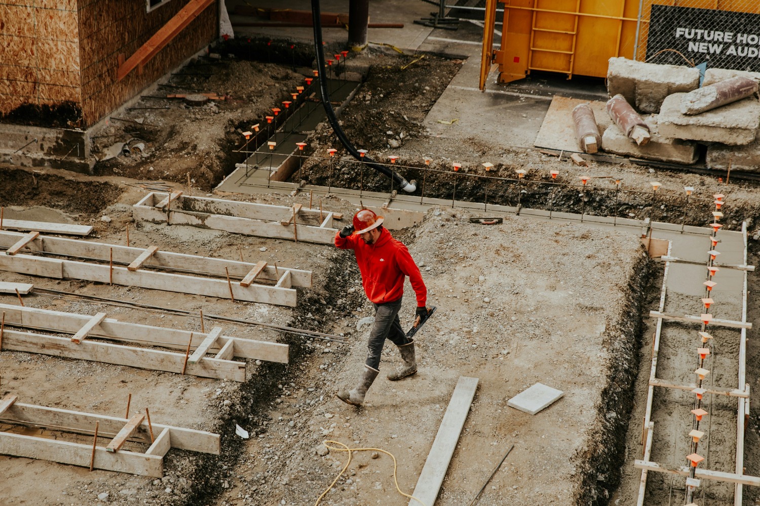 Worker in red sweatshirt walking through construction site